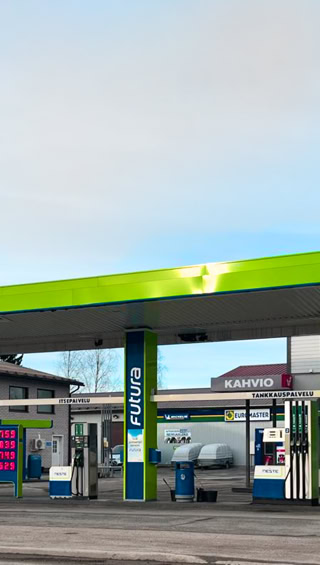 A gas station with a green and blue canopy, multiple fuel pumps, and a convenience store in the background.